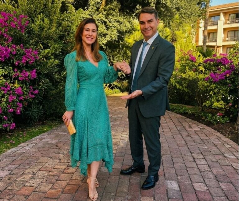Fernanda e o senador Flávio Bolsonaro posam durante evento diplomático no Chile. O casal aparece em clima de sintonia e elegância; ela veste vestido em renda artesanal verde da Martha Medeiros, enquanto ele opta por terno clássico, em registro que evidencia a cumplicidade dos dois na agenda internacional.