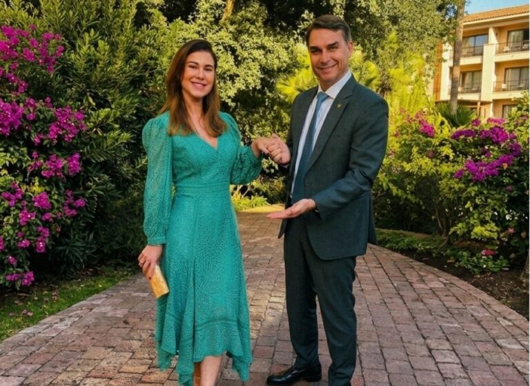 Fernanda e o senador Flávio Bolsonaro posam durante evento diplomático no Chile. O casal aparece em clima de sintonia e elegância; ela veste vestido em renda artesanal verde da Martha Medeiros, enquanto ele opta por terno clássico, em registro que evidencia a cumplicidade dos dois na agenda internacional.
